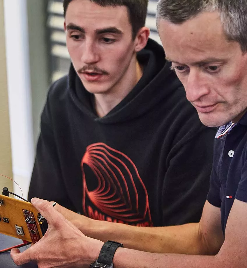 Professeur et étudiant travaillant l'éléctronique